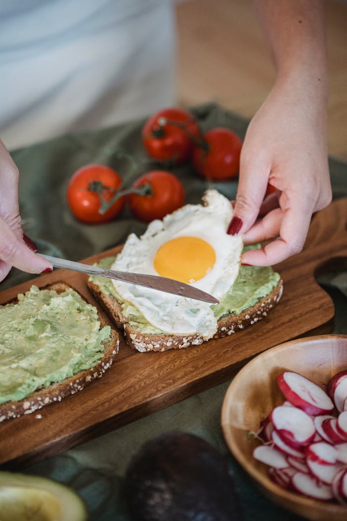 creative-03 Hands preparing avocado and fried egg toast for a healthy breakfast.